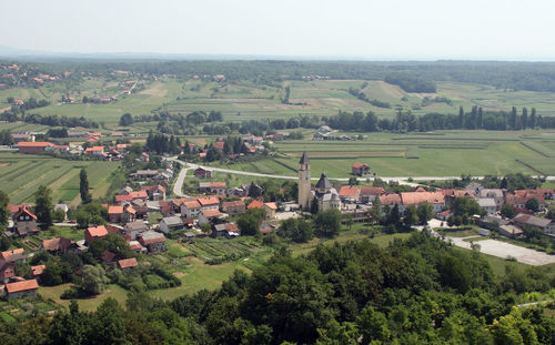 Scenic view of agricultural field by houses against sky