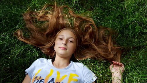High angle portrait of teenage girl lying on grass