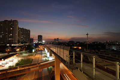 High angle view of illuminated street amidst buildings in city at night