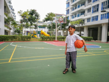 Full length of boy holding basketball at court