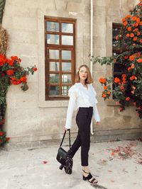 Full length of young woman standing outside house