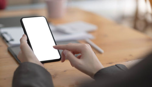 Midsection of man using mobile phone on table