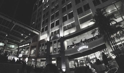 People on illuminated street amidst buildings in city at night