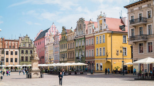 People on street amidst buildings in town against sky