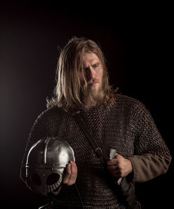 Viking with helmet and sword against black background