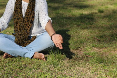 Low section of woman practicing yoga on grass