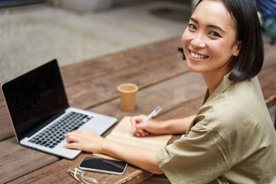 Young woman using laptop while sitting on table