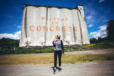 Full length of young woman standing against sky