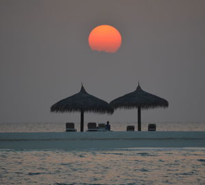 Built structure on beach against sky during sunset