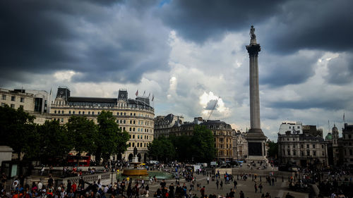 People at town square against cloudy sky