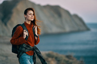 Portrait of smiling young woman standing against sea