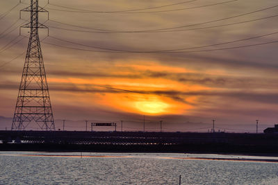 Silhouette electricity pylon against sky during sunset