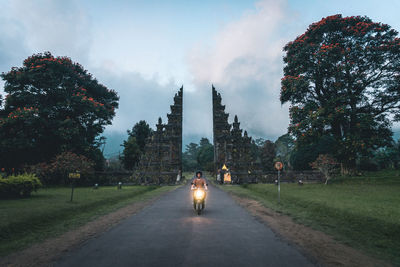 Mid adult man riding motorcycle on road amidst trees against sky