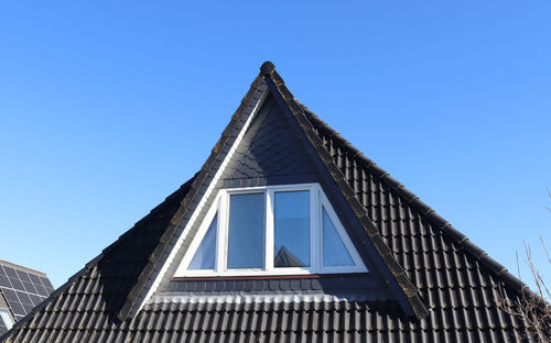 Open roof window in velux style with black roof tiles