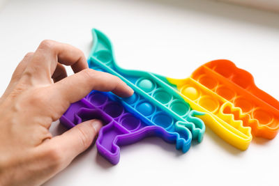 Close-up of hand holding toy against white background