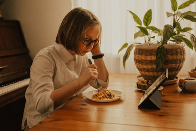 Young woman sitting on table at home