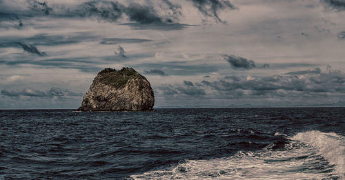 Scenic view of rocks on sea against sky