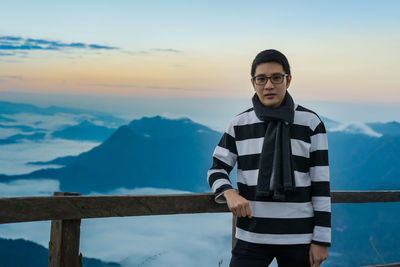 Portrait of smiling man standing on mountain against sky