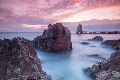 Scenic view of rocks on sea against sky during sunset