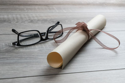 Close-up of certificate and eyeglasses on wooden table