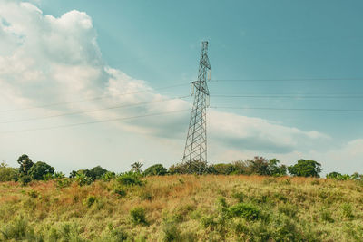 Low angle view of electricity pylon on field against sky