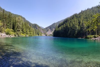 Scenic view of lake and mountains against clear blue sky