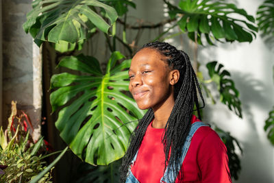 Portrait of young woman standing against plants