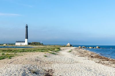 Lighthouse by sea against sky