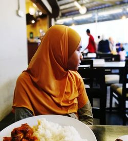 Rear view of people sitting on table at restaurant