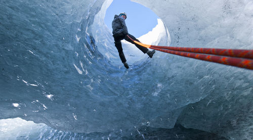Man rappelling into glacier cave on sólheimajökull glacier in iceland