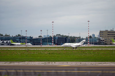 Airplane on runway against sky in city