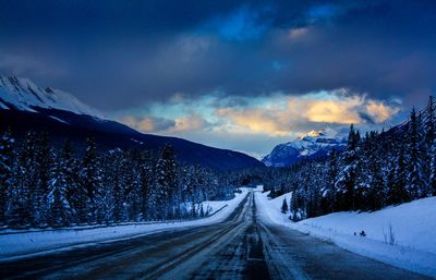 Road amidst snow covered mountains against sky