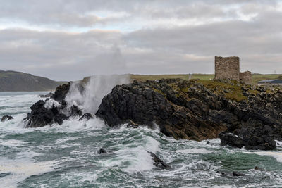 Waves smashing agains rocks with old fort in ireland