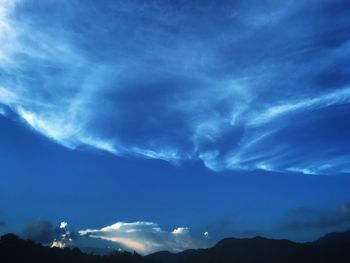 Low angle view of silhouette mountain against blue sky