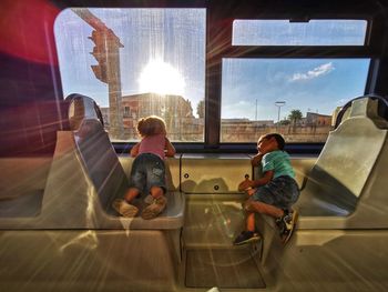 Rear view of people sitting on glass window