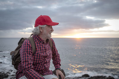 Woman wearing hat at beach against sky during sunset