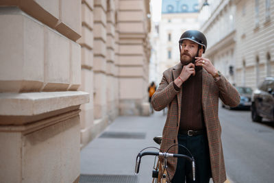 Portrait of businessman wearing bicycle helmet in city