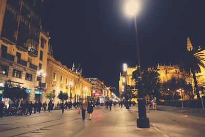 People walking on city street at night