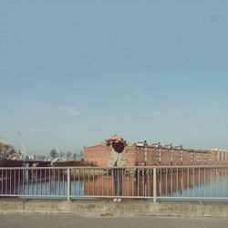 Man by railing against clear sky