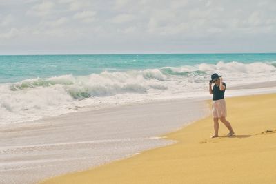 Rear view of woman on beach against sky