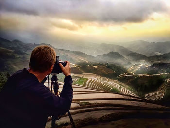 Man photographing on mountain against sky