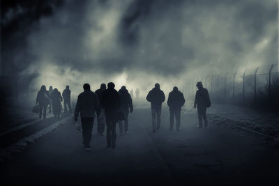 Silhouette people walking on road against sky