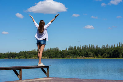 Rear view of man jumping in water against sky