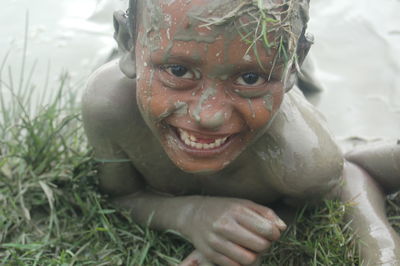 Close-up portrait of smiling boy in mud