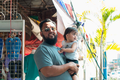 Asian bearded father carrying daughter.