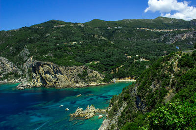 Scenic view of sea and mountains against blue sky