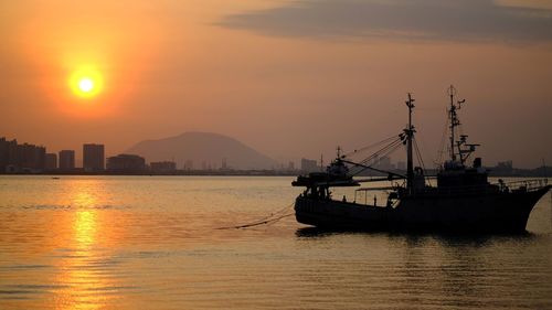 Silhouette ship in sea against sky during sunset