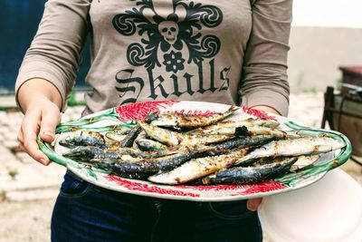 Midsection of woman holding sardines