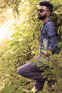 Side view of young man standing by plants