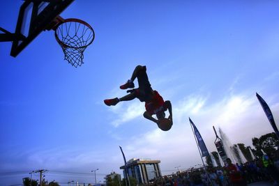 Low angle view of people jumping against clear sky